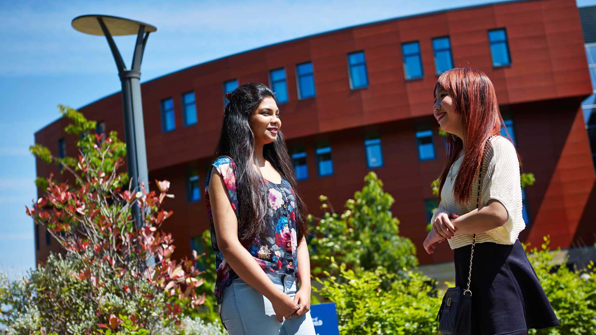 A photo of two female students stood on the grass outside the business school.